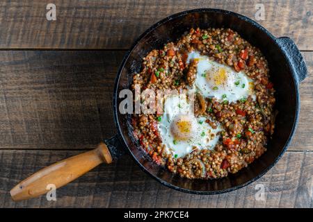 Gekochter Buchweizen mit Spiegeleiern, Paprika, Karotten und Zwiebeln, Nahaufnahme, Ukraine. Hintergrund für das Essen. Gesunde Ernährung Stockfoto