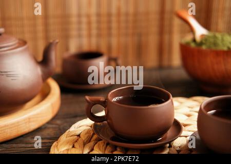 Teezeremonie. Traditionelles Asiatisches Teeutensil, Serviert Authentisches Set. Person, die Tee von der Teekanne aus brauner Keramik bis zur Teekanne einschenkt. Bambusschale. Lifestyle. Wir Stockfoto