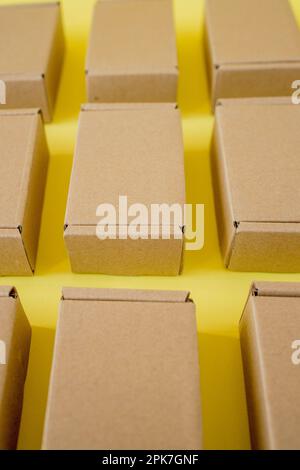 Viele Kraftkarton-Boxen auf gelbem Hintergrund. Ich packe das Paket Stockfoto