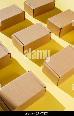 Viele Kraftkarton-Boxen auf gelbem Hintergrund. Ich packe das Paket Stockfoto