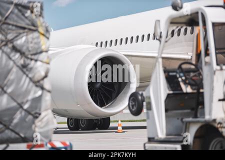 Vorbereitung des Flugzeugs am Flughafen. Beladung von Frachtcontainern gegen Strahltriebwerke des Flugzeugs vor dem Flug. Stockfoto