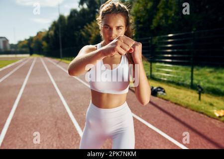 Kickboxen üben. Eine junge Frau in Sportkleidung trainiert draußen Stockfoto