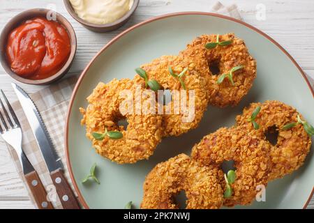 Panierte Hühnchen-Donuts aus gezogenem Hühnchen mit Gemüse und frittierten Nahaufnahmen auf einem Teller auf dem Tisch. Horizontale Draufsicht von oben Stockfoto