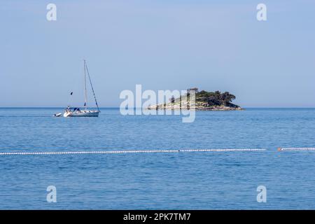 ROVINJ, KROATIEN - 15. MAI 2022 Vergnügungsyacht, vorbei an einer kleinen Insel in der Adria mit einer Linie weißer Bojen Stockfoto