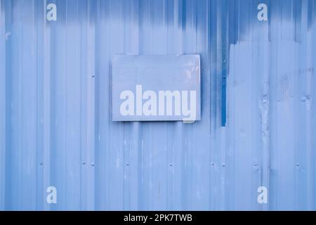 Ein gemaltes Schild an einer blau gestrichenen Gebäudewand. Stockfoto