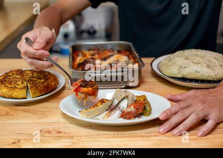 Ein Mann, der Gerichte, Teller mit italienischem Essen zubereitet, auf einem Restaurantschalter. Stockfoto