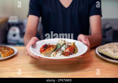 Ein Mann steht an einer Restauranttreppe und präsentiert gekochte Speisen und Menügerichte. Stockfoto