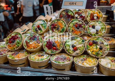 Mischen Sie den Salat auf dem Markt in Papierkartons. Lieferung biologisch abbaubarer Behälter. Das Konzept der Mitnahme. Stockfoto