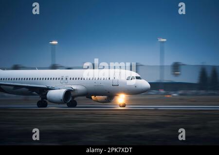 Gewerbliche Flugzeuge während des Starts auf der Start- und Landebahn des Flughafens bei Nacht. Ebene in unscharfer Bewegung. Stockfoto