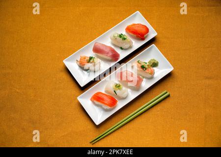 Sushi-Platte, eine Auswahl an rohem Fisch und Reissnacks mit Stäbchen. Stockfoto