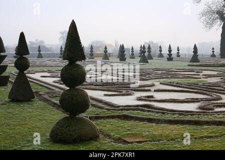 Topische Eiben mit Pyramiden- und kugelförmigen Formen im winterlichen Palastgarten. Stockfoto