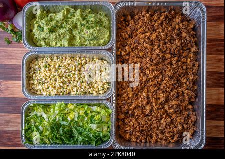 Eine Vielzahl von Zutaten in mehreren Behältern, die zur Herstellung eines mexikanischen Gerichts verwendet werden, wie z. B. Tacos Stockfoto