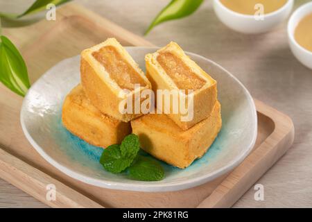 Köstliches taiwanesisches Ananaskuchen Gebäck auf einem Teller auf Holztisch mit heißem Tee. Stockfoto
