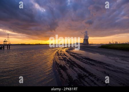 Farbenprächtiger Sonnenuntergang über dem Antwerpener Welthafen in Belgien mit Blick auf die Türme des Atomkraftwerks Stockfoto