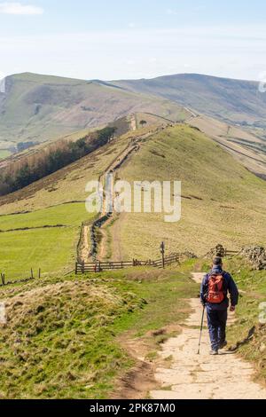 Ein Mann, der mit dem Rucksack auf dem großen Hügel in Richtung Back Tor und Mam Tor in Castleton im Derbyshire Peak District England spaziert Stockfoto