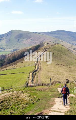 Ein Mann, der mit dem Rucksack auf dem großen Hügel in Richtung Back Tor und Mam Tor in Castleton im Derbyshire Peak District England spaziert Stockfoto