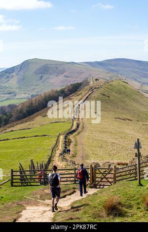 Ein Mann, der mit dem Rucksack auf dem großen Hügel in Richtung Back Tor und Mam Tor in Castleton im Derbyshire Peak District England spaziert Stockfoto