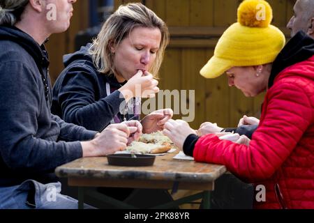 Bild einer Gruppe von Frauen, die in Szeged, Ungarn, Langos essen. Langos ist ein typisch ungarisches Street Food. Heute ist es ein frittiertes Fladenbrot, aber in dem Stockfoto