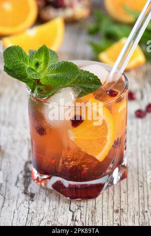 Der Cocktail wird aus Granatapfel und Orangensaft mit Tequila oder Gin mit Tonic hergestellt. Serviert in einem Glas mit Eis und Orangenscheiben Stockfoto