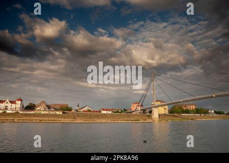 Bild einer Hängebrücke in der Stadt Sremska Mitrovica im Norden Serbiens, die den Fluss Sava überquert, mit dem Stadtzentrum der Stadt in Srems Stockfoto