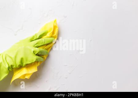 Grüner Handschuh mit Mikrofaser-Rag-Reinigung Weiße Oberfläche mit Reinigungsschaum Stockfoto