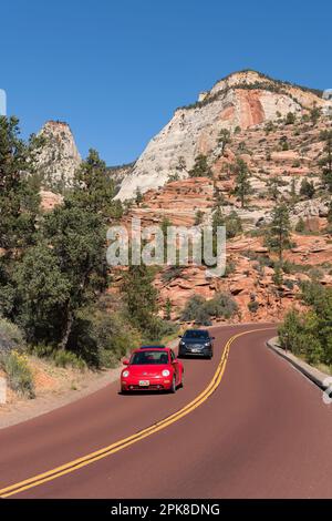 Red VW Beetle: Fahrt auf der malerischen Straße Zion-Mount-Carmel-Highway, die sich an den majestätischen Sandsteinklippen des östlichen Zion-Nationalparks vorbei schlängelt Stockfoto