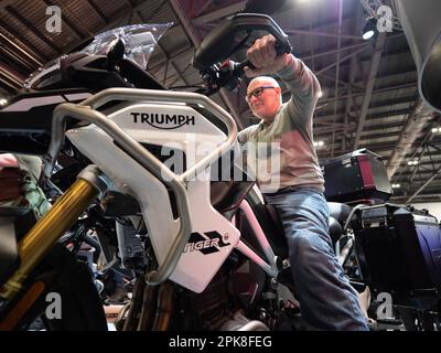 Szenen auf der Carole Nash MCN London Motorcycle Show Excel London, Triumph Stand mit Kunde sitzt auf Triumph Tiger Stockfoto
