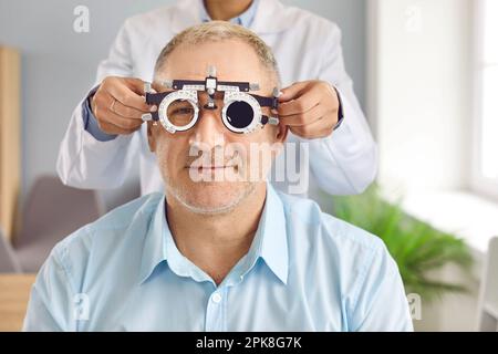 Optometrist oder Ophthalmologe verwendet spezielle Geräte, um das Sehvermögen reifer Patienten zu testen Stockfoto