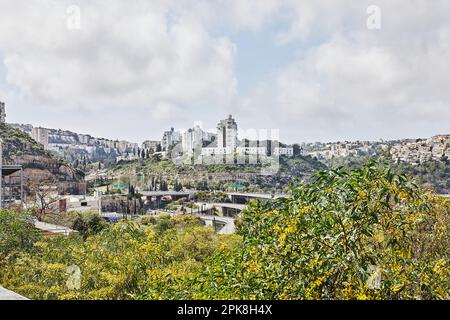 Straßenkreuzung in Haifa City und Stadthäuser im Frühling im Grünen. Stockfoto