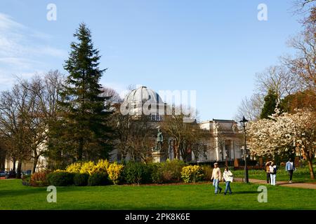 Wetter in Großbritannien 4. April 2023. Cardiff, Südwales. An einem sonnigen frühen Frühlingsnachmittag genießen die Menschen einen Spaziergang durch die Goresedd Gardens. Das gewölbte Gebäude im Hintergrund ist das National Museum Cardiff, ein Museum und eine Kunstgalerie, die Teil des Museum Wales ist. Stockfoto