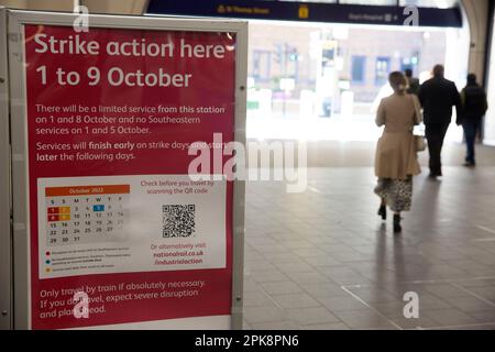 Die Leute gehen an einer Informationstafel vorbei, die die Passagiere über die Arbeitskampagne am Londoner Bahnhof Bridge informiert. Stockfoto