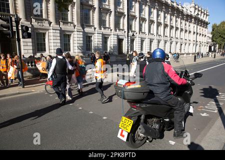 Aktivisten von „Just Stop Oil“ versuchen, ein Banner vor dem Verkehr in Westminster im Zentrum von London zu halten. Stockfoto
