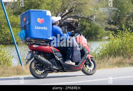 BANGKOK, THAILAND, FEBRUAR 07 2023, Ein Auslieferer fährt ein Motorrad mit einem Lieferkarton Stockfoto