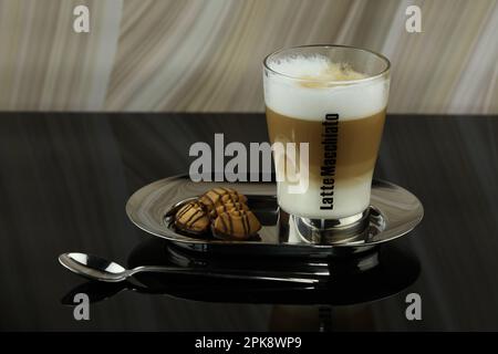 Ein Glas Latte Macchiato auf einem Teller mit Keksen. Stockfoto