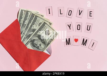 Geld in roten Umschlägen. Glückwunsch zum Muttertag Begrüßungsgeschenk, verschlossen von einem Haufen US-Dollar-Banknoten. Banknoten, die als Geschenk in einem Umschlag gefaltet wurden Stockfoto