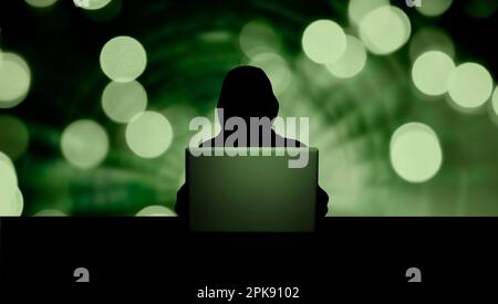Dunkle Person mit Kapuze vor offenem Laptop und digitalem Hintergrund Stockfoto