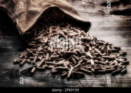 Holzpellets mit Jutesack auf rustikalem Holzhintergrund Stockfoto