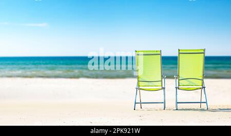 Zwei Sonnenliegen am Strand vor dem blauen Meer [M] Stockfoto