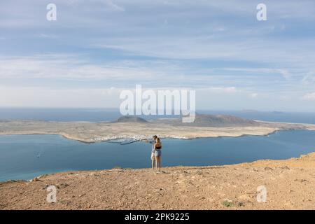 Zwei Touristen stehen am Mirador del Rio und schauen auf La Graciosa, Kanarische Inseln Stockfoto