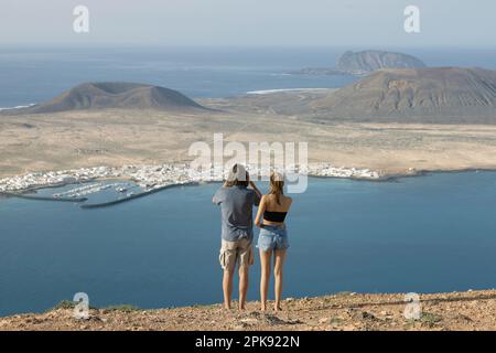 Zwei Touristen stehen am Mirador del Rio und schauen auf La Graciosa, Kanarische Inseln Stockfoto