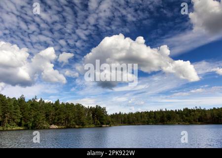 Unterschiedliche Wolken über einem See und Wald in den Schären Schwedens Stockfoto