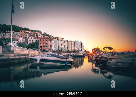 Der kleine Hafen von Moö?eni?ka Draga am Morgen, im Hintergrund das Stadtzentrum bei Sonnenaufgang am Mittelmeer in Istrien, Kroatien Stockfoto