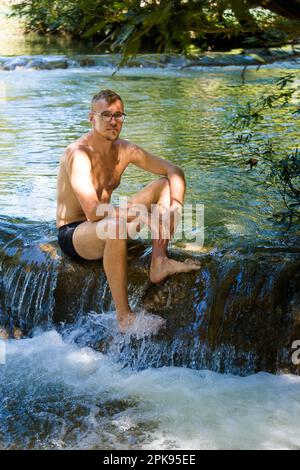 Junger, gutaussehender Mann in Roberto Barrios cascadas Park, Palenque in Mexiko. Lebendiges Landschaftsfoto mit üppigem Grün und kristallklarem Wasser an sonnigen Tagen. Stockfoto