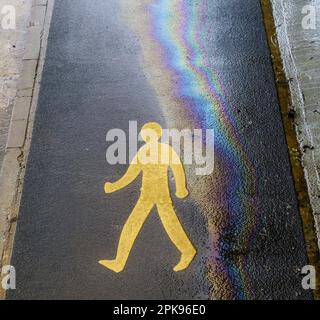 Fußgängerschild mit Öl- und Wasser-Regenbogeneffekt auf Asphalt. Eco-Öl-Konzept. Stockfoto