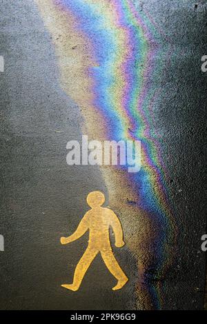 Fußgängerschild mit Öl- und Wasser-Regenbogeneffekt auf Asphalt. Eco-Öl-Konzept. Stockfoto