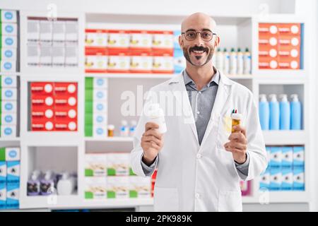 Junger hispanic-Mann Apotheker hält Pillen Flaschen in der Apotheke Stockfoto