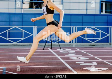 Läuferin überquert die Ziellinie auf der Stadionstrecke und springt im Leichtathletikwettbewerb Stockfoto