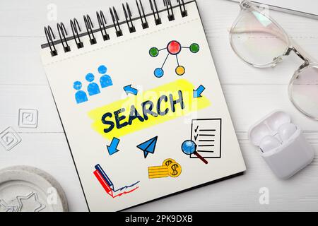 SEO-Konzept. Notizbuch mit WORTSUCHE und verschiedenen Zeichnungen auf weißem Holztisch, flach liegend Stockfoto