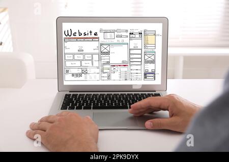 Designer erstellt Website auf Laptop am weißen Tisch, Nahaufnahme Stockfoto
