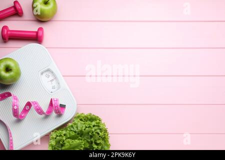 Flache Bettwäsche mit Badezimmerwaage und Maßband auf rosa Holzboden, Platz für Text. Gewichtsverlust-Konzept Stockfoto